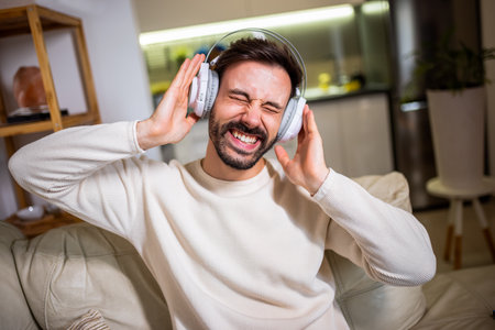 A young man relaxing at home while listening to music through headphones.の写真素材