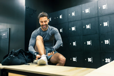 Fit handsome man gets ready to workout in the dressing room of the gym.