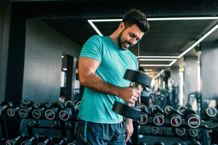 Fit man using dumbbells in the gym to train arms.の写真素材