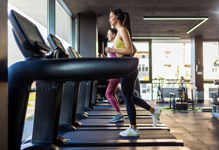 Two women run on a treadmill.