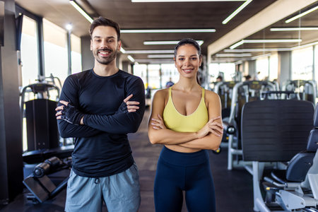 Two gym partners pose with their arms crossed in the gym.の写真素材