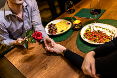 Loving boyfriend gifts a red rose to his girlfriend on a romantic dinner date.の写真素材