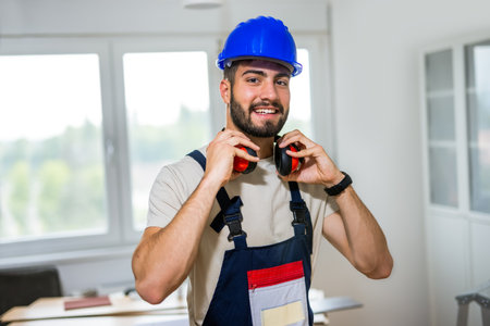 Portrait of young man working diligently on renovating his apartment, focusing on the installation of laminate flooring. With the right tools in hand, he carefully measures and fits the laminate panels into place, transforming the space with his DIY skills.の写真素材