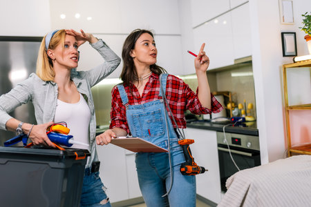 Two girls are standing in a room with tools in their hands, ready to start fixing and renovating the house.の写真素材