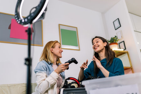 Two young girls are recording a video for social media. They are showing how to recycle old computer...