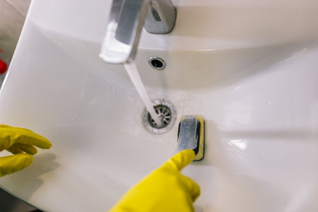 A close-up shot of a woman cleaning a faucet.の写真素材