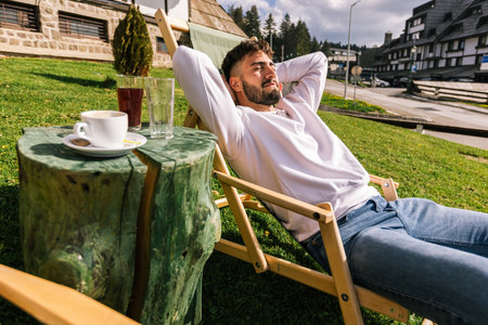 A young man relaxes on a lounge chair at a mountain resort during a sunny weekend escape.