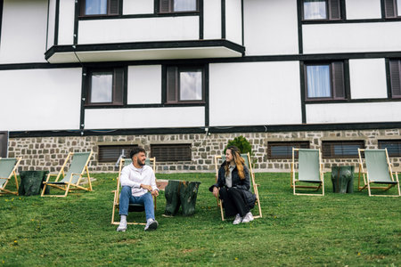 A young couple enjoys a peaceful weekend retreat at a scenic mountain resort. Lying on lounge chairs, they soak up the fresh alpine air.の写真素材