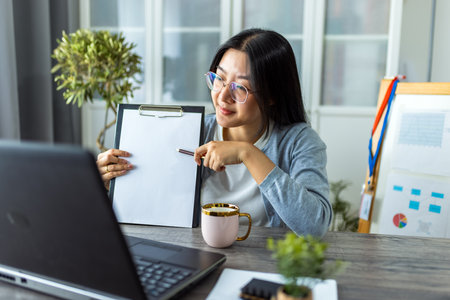 A young Thai woman is working from home and participating in a business video call.の写真素材