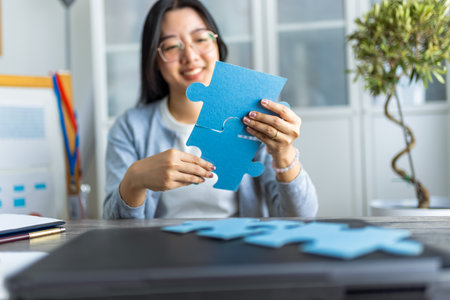 A young Thai woman is working from home on her computer while taking a break to complete a puzzle.の写真素材
