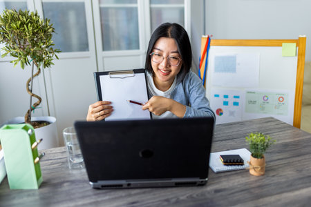 A young Thai woman is working from home and participating in a business video call.の写真素材