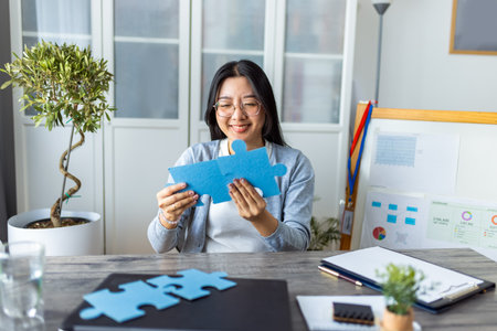 A young Thai woman is working from home on her computer while taking a break to complete a puzzle.の写真素材