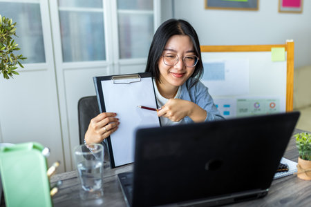 A young Thai woman is working from home and participating in a business video call.の写真素材