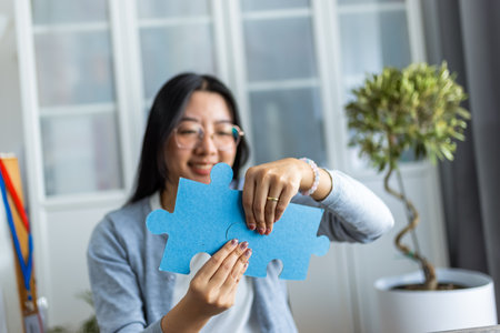 A young Thai woman is working from home on her computer while taking a break to complete a puzzle.の写真素材