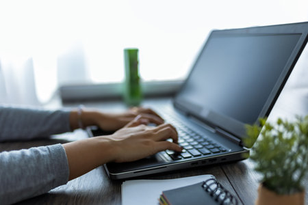 A young Thai woman is working from home, focused on her computer in a cozy home office setting.の写真素材