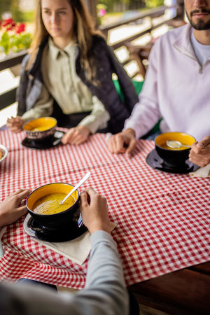 Brothers and sister having lunch together on the terrace of a mountain restaurant during a bright spring or autumn day.の写真素材