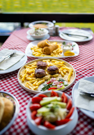 Delicious lunch served on a restaurant terrace table, featuring a fresh salad, meatballs, and a...