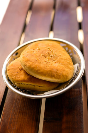 Freshly baked flatbreads arranged on a rustic wooden table.の写真素材