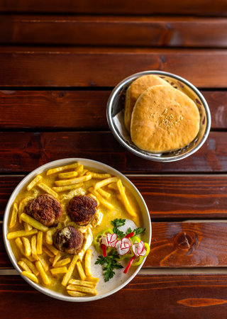 Juicy meatballs served with golden French fries on a white plate. A hearty, classic comfort meal captured in natural light.の写真素材