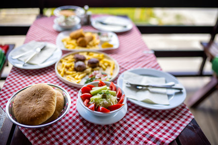 Delicious lunch served on a restaurant terrace table, featuring a fresh salad, meatballs, and a rolled meat schnitzel.の写真素材