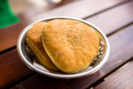 Freshly baked flatbreads arranged on a rustic wooden table.の写真素材