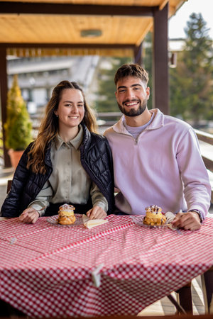 Young couple enjoying cream-filled profiteroles together on the terrace of a mountain restaurantの写真素材