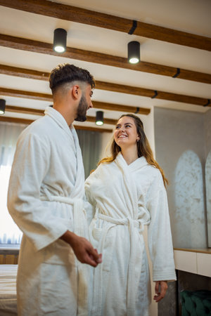 A couple dressed in bathrobes stands in their hotel room, gazing into each otherâs eyes with warmth and affection.の写真素材