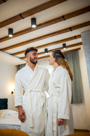 A couple dressed in bathrobes stands in their hotel room, gazing into each otherâs eyes with warmth and affection.の写真素材