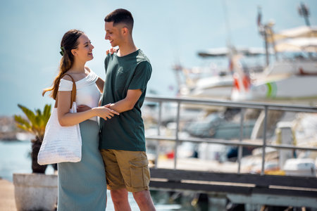 A romantic couple holds each other closely while standing by the yachts docked at the sea. They gaze into each otherâs eyes, sharing an intimate and loving moment.の写真素材