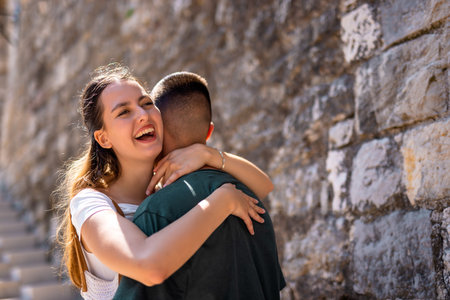 A young couple shares a warm embrace while standing on the ancient walls of a historic old city during their summer holiday.の写真素材