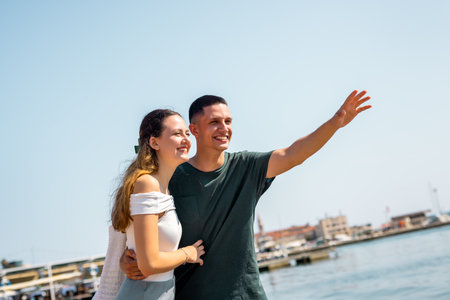 A loving couple walks along the shore on a warm summer day, with the boyfriend gently holding his girlfriend around the waist.の写真素材
