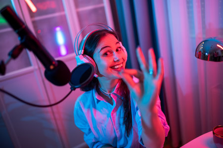 A young woman is recording her own podcast in a modern home studio setup, surrounded by professional equipment.の写真素材