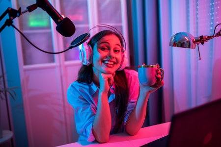 A young woman is recording her own podcast in a modern home studio setup, surrounded by professional equipment.の写真素材