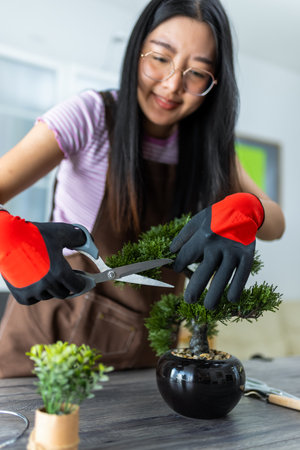 A young Thai girl carefully trims her bonsai tree, practicing patience and precision.の写真素材