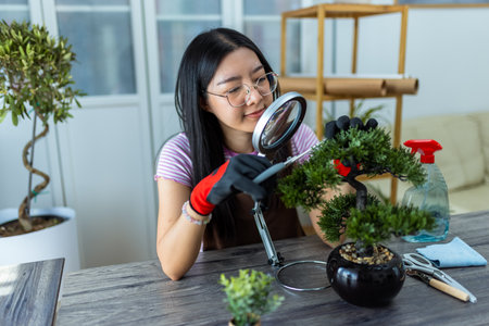 A young Thai girl carefully trims her bonsai tree, practicing patience and precision.の写真素材
