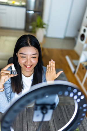 A young Thai influencer proudly shows off her freshly painted nails while filming a beauty video with a ring light.の写真素材