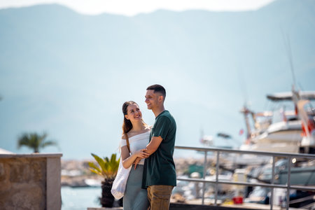 A young couple stands closely on a marina deck, holding on to each other and gazing into each otherâs eyesの写真素材