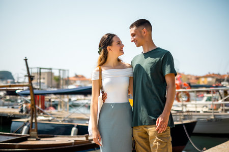 A young couple stands closely on a marina deck, holding on to each other and gazing into each otherâs eyesの写真素材