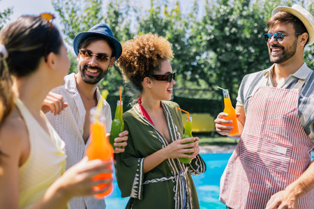 A lively group of young people dance and have fun by the pool, sipping colorful cocktails with...
