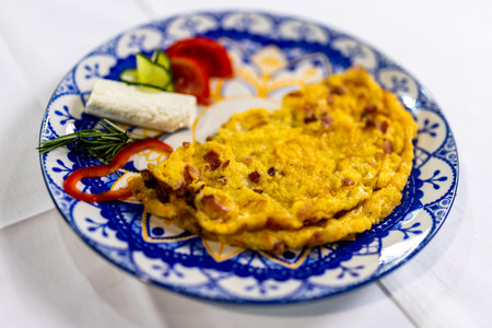 Tasty scrambled eggs with crispy bacon, served with fresh tomato, cucumber slices, and cheese on the side â a perfect breakfast plate.の写真素材