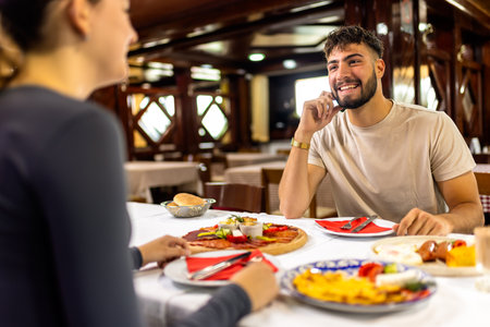 A couple sitting at a resort restaurant table, ready to enjoy a hearty breakfast with eggs, ham, vegetables, bread, and other delicious morning dishes.の写真素材