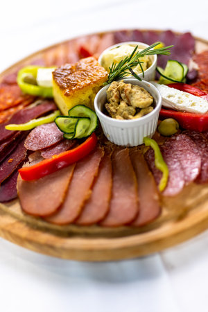 A delicious Serbian meza plate with assorted cured meats, cheese, olives, bread, paprika, and cream â perfect for sharing and traditional gatherings.の写真素材