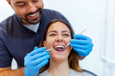 Male dentist performing dental treatment on female patient in modern clinic. Focus on professional...