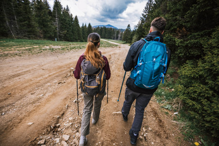 Male and female hikers with full gear trek through stunning mountains, wearing boots, backpacks, and...
