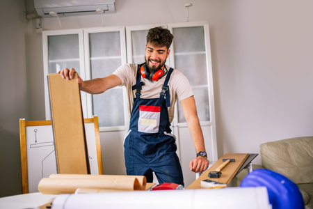 Repairman in an apartment holds a laminate plank, preparing to repair the floor with precision and...