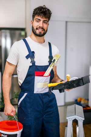 Painter in an apartment prepares to paint walls, holding brushes, ready to start a fresh and precise renovation.の写真素材