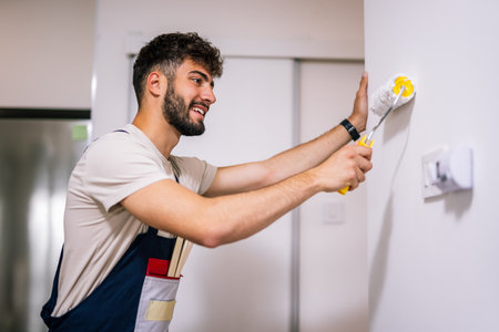 Painter in an apartment applies lime to walls with brushes, working on a fresh and precise interior renovation.の写真素材