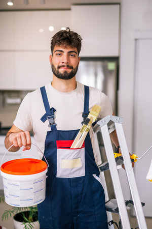 Painter in an apartment prepares to paint walls, holding lime and brushes, ready to start a fresh and precise renovation.の写真素材