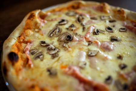 Classic Italian pizza with ham and mushrooms served hot on a plate in a restaurant.の写真素材