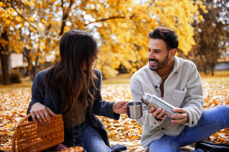 Relaxed young couple enjoying a moment together in colorful autumn park, romantic and cozy fall scene.の写真素材
